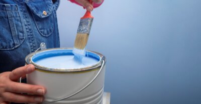 light blue colored paint with a man holding and dipping a paint brush
