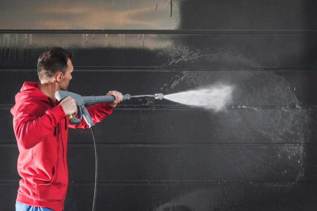 man pressure washing a wall