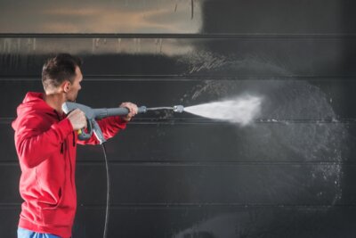 man pressure washing a wall