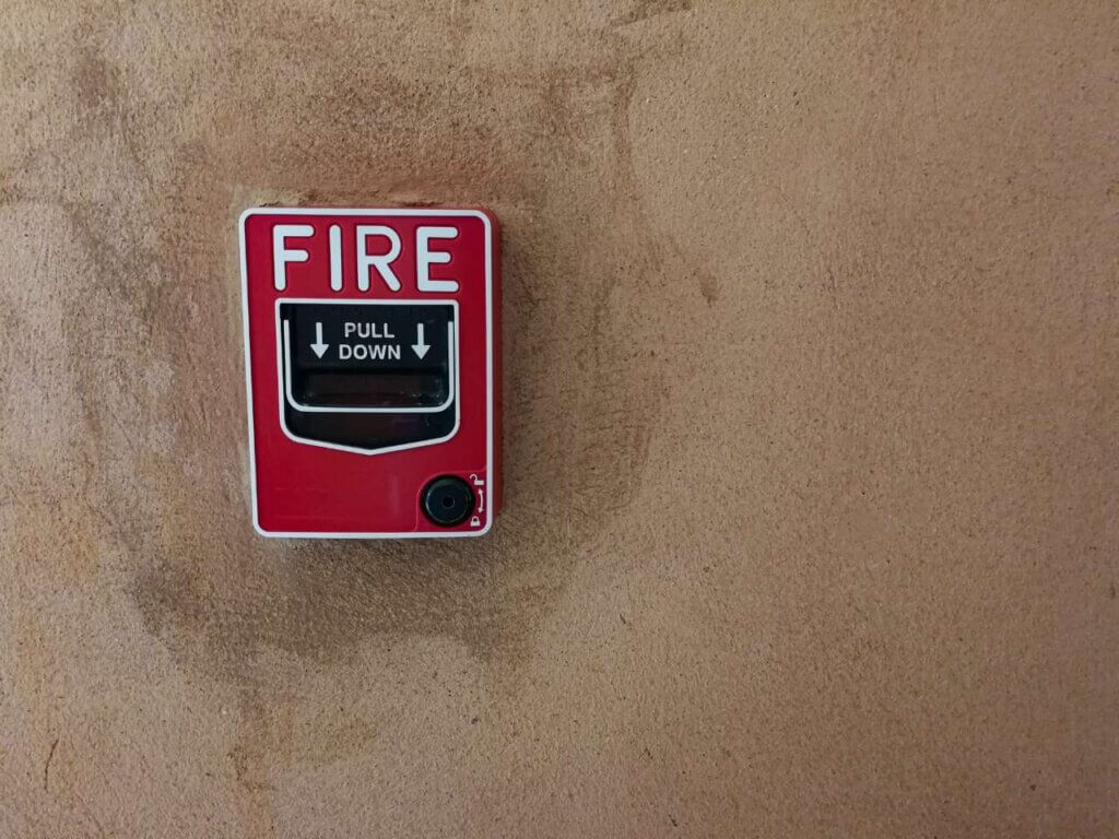 fire break glass alarm switch on a concrete wall