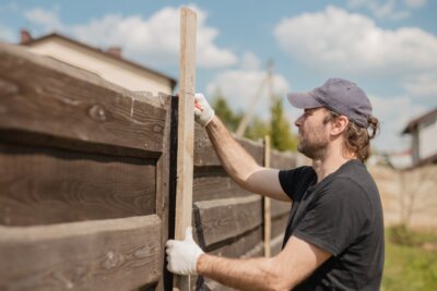 Man builds sections of fence around his yard out of planks