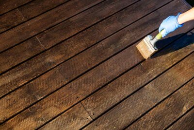 hand holding a brush with deck sealer